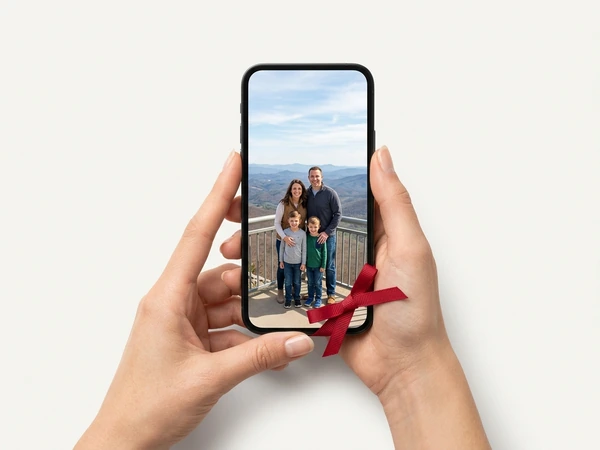 Hands holding a phone showing a family photo at a mountain lookout