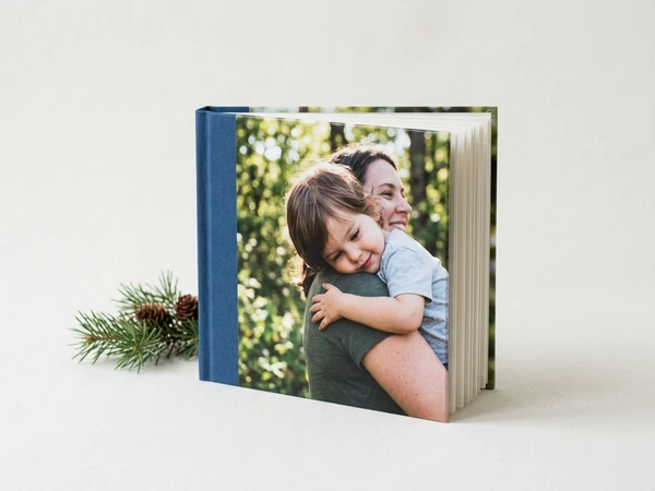 Blue photo book with a cover photo of a toddler hugging his mother