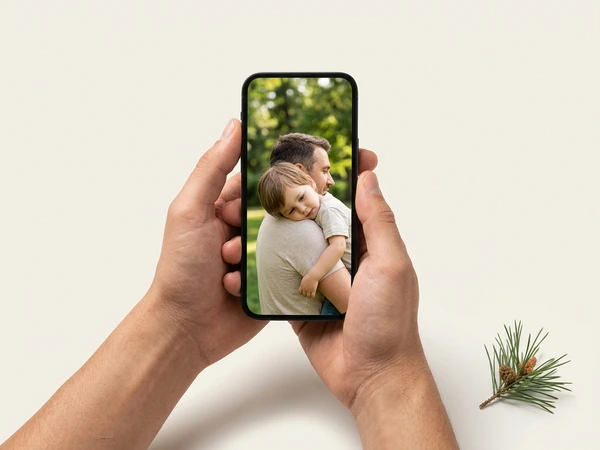 Hands holding a phone with a photo of a father carrying his child