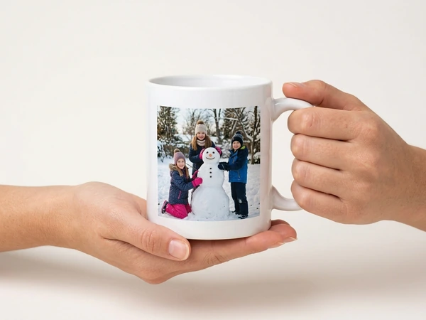 Hands presenting a finished photo mug of three children beside a snowman