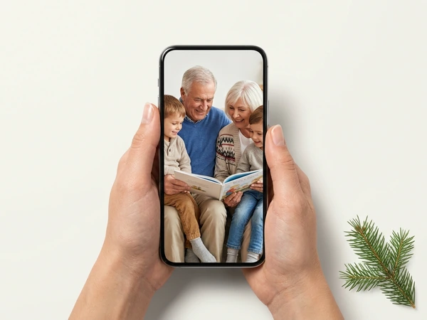 Hands holding a phone with a photo of grandparents reading to grandchildren
