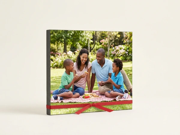 Photo board tied with red ribbon of a family eating on a picnic blanket