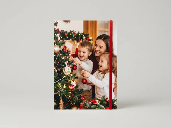 Classic poster of a woman, a boy and a girl hanging red ornaments on a Christmas tree