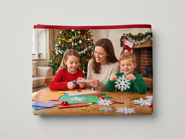 Fleece blanket of a woman, a girl and a boy cutting paper snowflakes at a craft table
