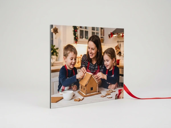 Photo board of a woman, a boy and a girl in aprons building a gingerbread house