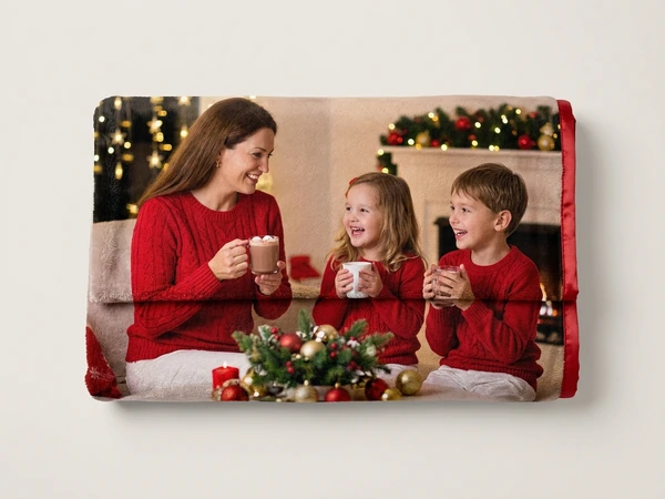 Plush blanket of a woman, a girl and a boy in red sweaters sipping hot cocoa by the fire