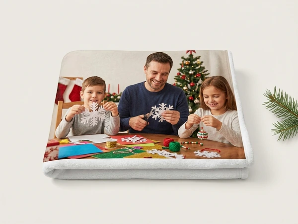 Fleece blanket of a man and two children cutting paper snowflakes at a craft table