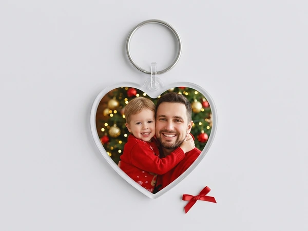 Clear heart keychain of a smiling man hugging a small boy in a red sweater