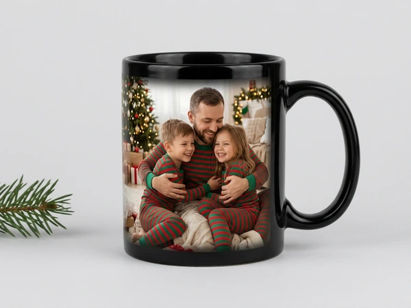 Black magic mug of a man hugging two children in striped pajamas by a Christmas tree