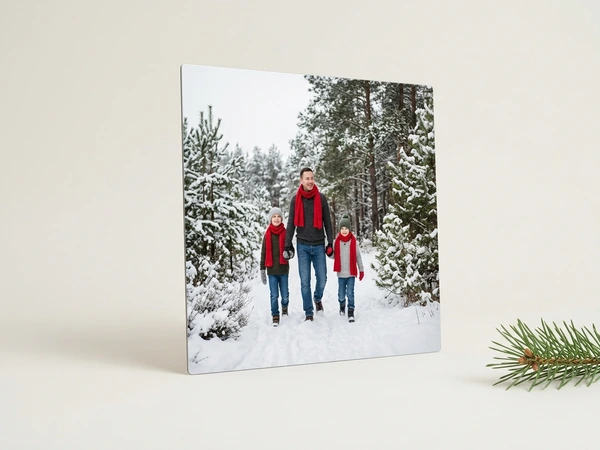 Metal print of a man in a red scarf walking hand in hand with two children on a snowy forest path