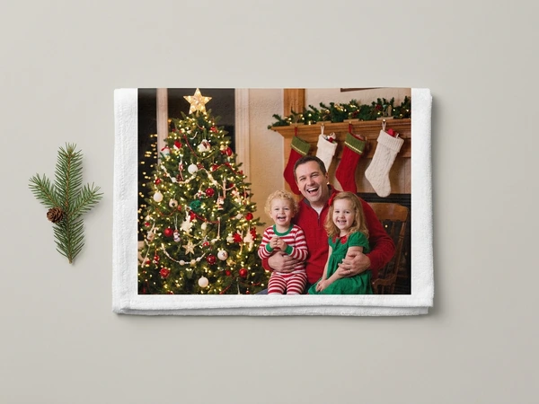 White photo towel of a man with two small children on his lap by a tree and hung stockings