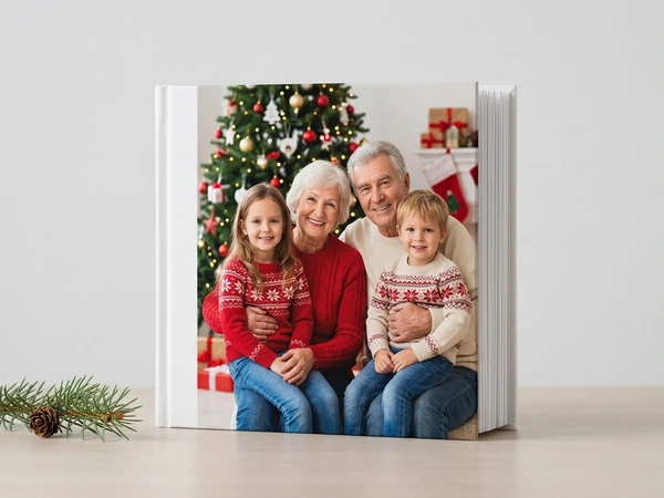 White photo book of grandparents with a girl and a boy in sweaters by a Christmas tree
