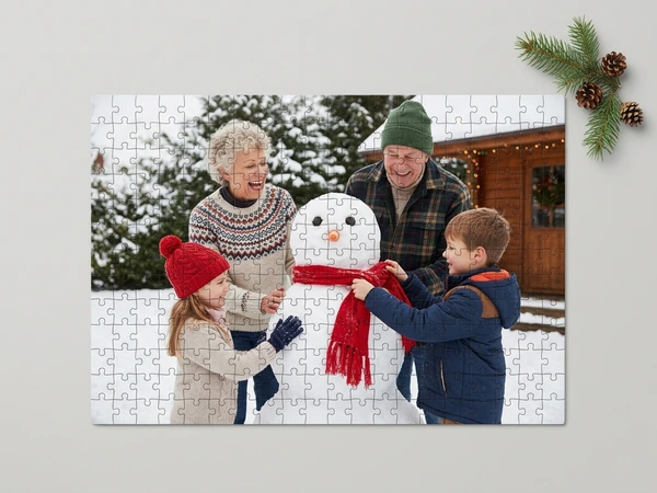 Photo puzzle of grandparents building a snowman with a girl and a boy in the snow