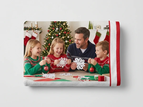 Fleece blanket of a man and three children cutting paper snowflakes at a table