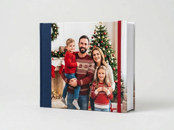 Photo book with a navy spine of a family of four posing by a Christmas tree