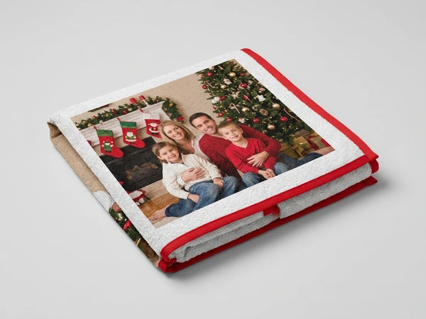 White photo towel with red trim of a family of four by a Christmas tree and stockings