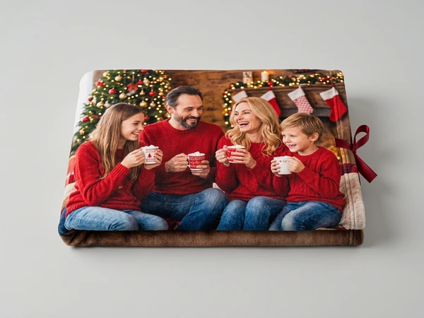 Plush blanket of a family of four in red sweaters sharing mugs by the fireplace