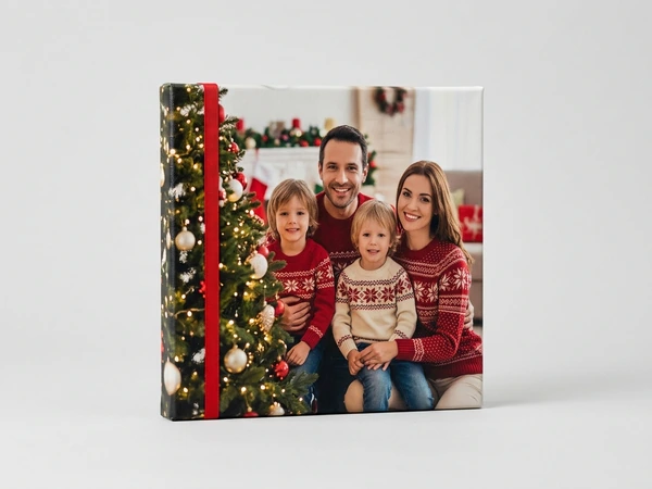 Square canvas of a family of four in red patterned sweaters beside a Christmas tree