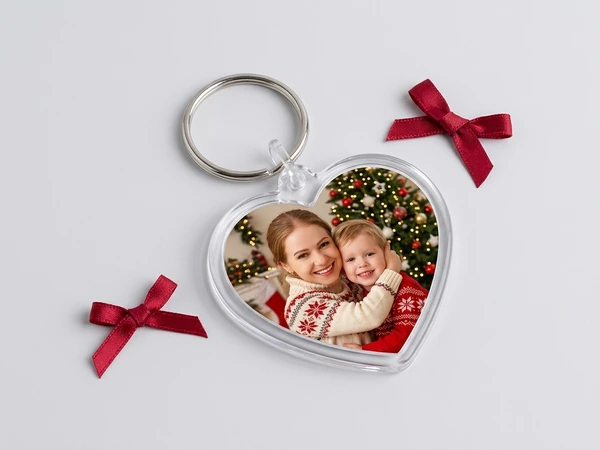 Heart keychain of a woman cuddling a young child in front of a Christmas tree