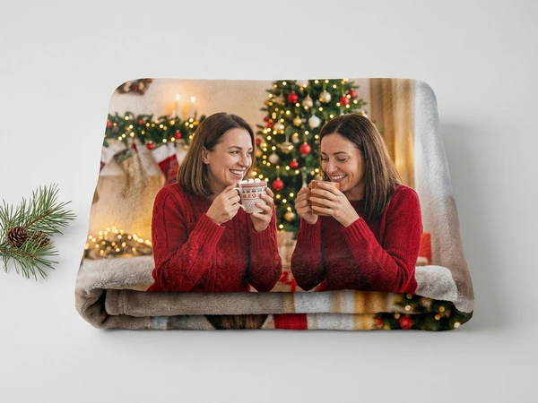 Plush blanket of two women in red sweaters sharing hot drinks by a Christmas tree