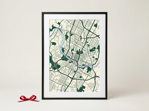 Black framed city map poster with green streets and a winding river on cream