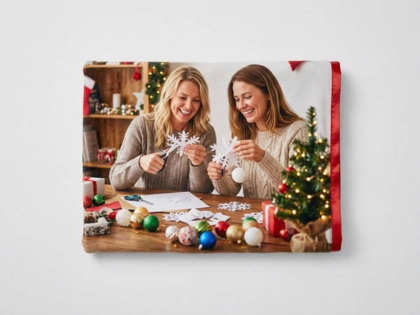 Fleece blanket of two women cutting paper snowflakes at a table with ornaments