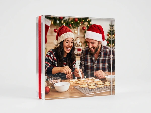 MixBlox of a man and a woman in Santa hats decorating star cookies in a kitchen