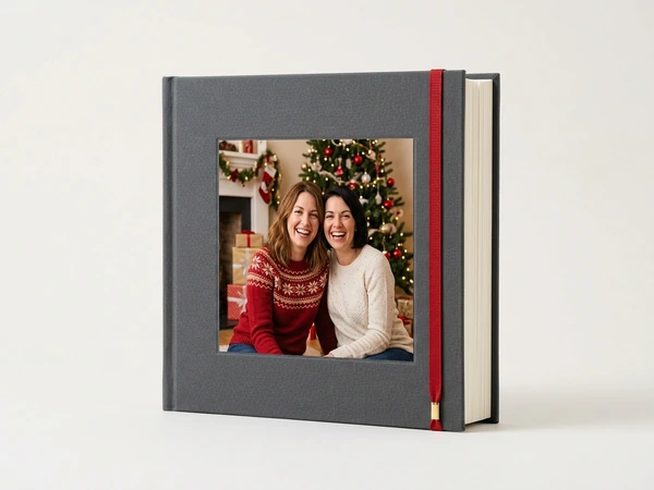 Gray linen photo book of two women in sweaters smiling in front of a Christmas tree