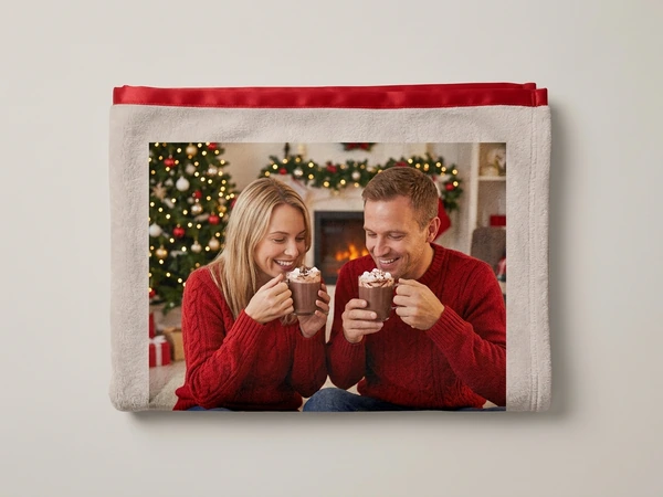 Plush blanket of a man and a woman in red sweaters sipping cocoa by a Christmas tree