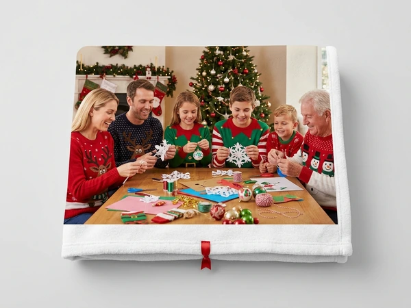 Fleece blanket of a family of six making paper snowflakes at a table by a Christmas tree