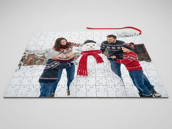 Photo puzzle of a man, a woman and two children building a snowman with a red scarf