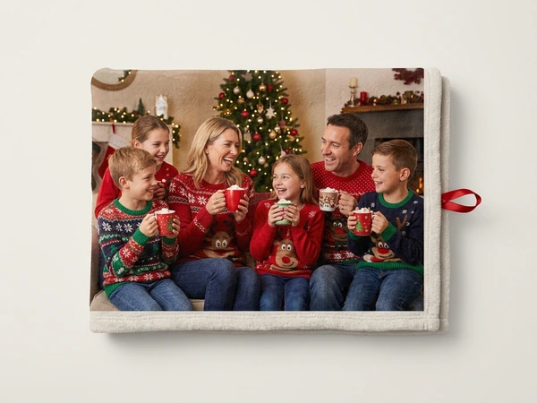 Plush blanket of a family of six sharing hot drinks on a sofa by a Christmas tree
