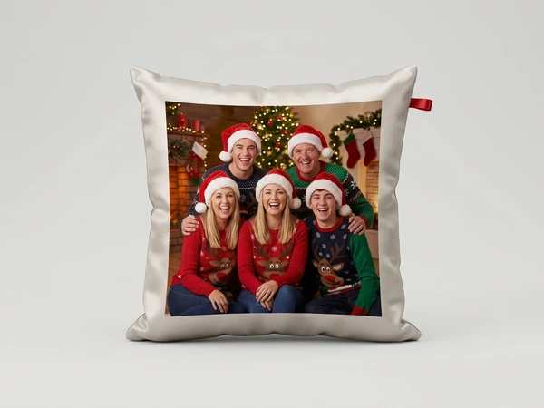 Satin pillow of five friends in Santa hats and festive sweaters by a decorated fireplace