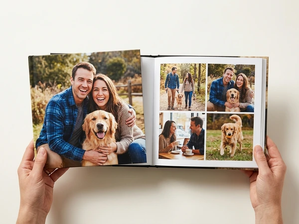 Hardcover photo book open on photos of a couple and their dog
