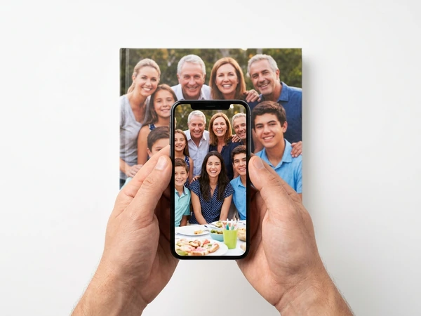Phone held over a photo book, showing the family photo that is printed on its cover