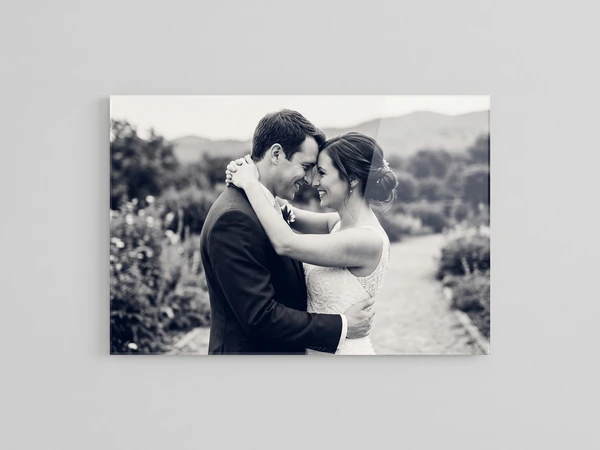 Black and white acrylic print of a bride and groom embracing on a country path