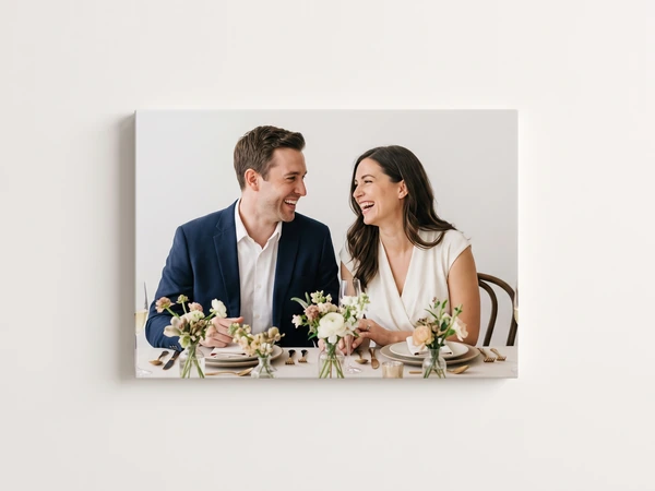 Canvas print of a couple laughing at a dinner table set with small flower arrangements