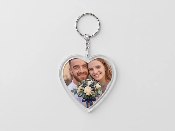 Heart keychain on a chain with a photo of a couple holding white roses tied with a blue ribbon
