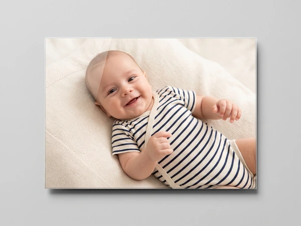 Acrylic print of a smiling baby in a striped bodysuit lying on a white blanket