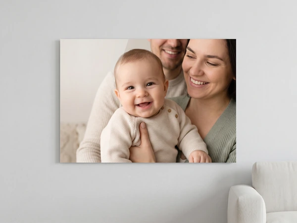 Acrylic print of a laughing baby held by smiling parents, hung beside a white chair