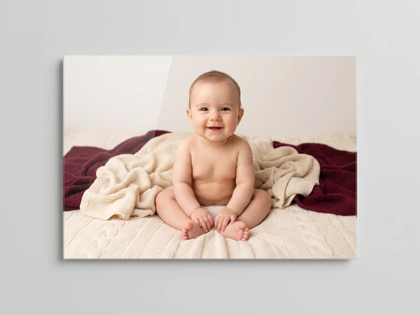 Acrylic print of a smiling baby sitting on a cream knit blanket with a burgundy throw
