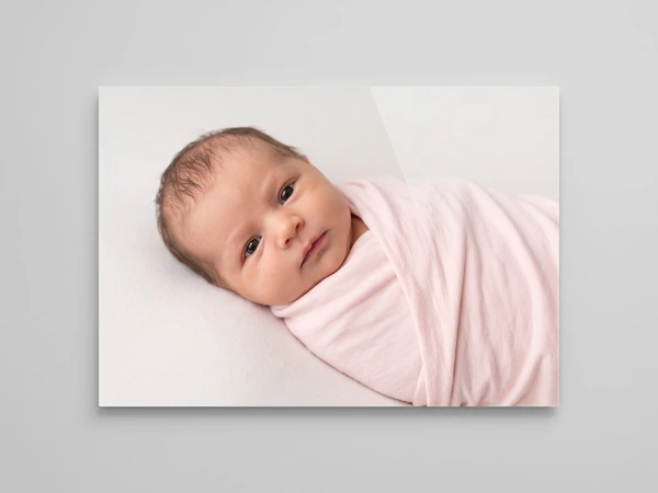 Acrylic print of a wide-eyed newborn wrapped in a pink blanket