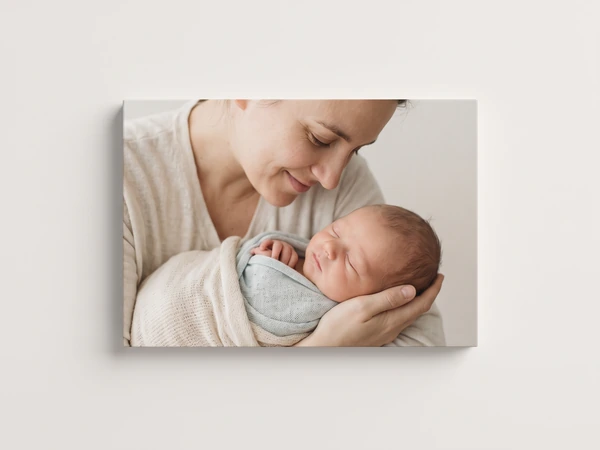 Canvas print of a mother looking down at a newborn swaddled in pale blue