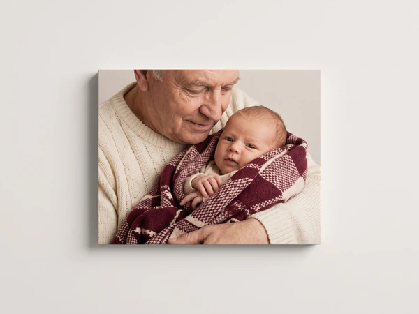 Canvas print of a grandfather holding a newborn wrapped in a red check blanket