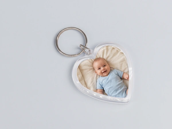 Heart keychain lying flat with a photo of a smiling baby in a blue bodysuit