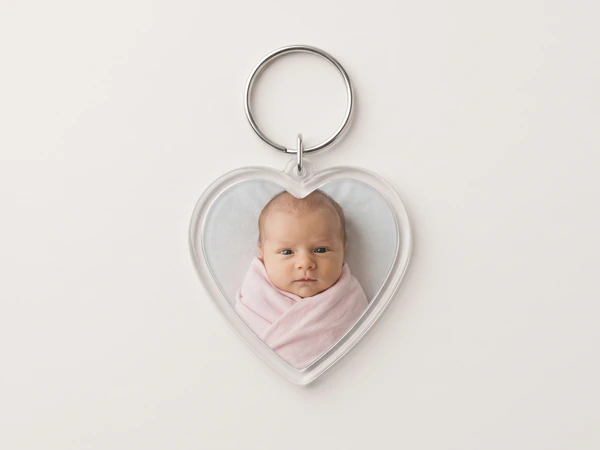 Heart keychain with a photo of a newborn wrapped in a pink blanket