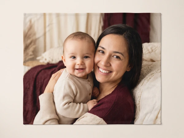 Photo blanket printed with a mother and smiling baby cuddled on a bed