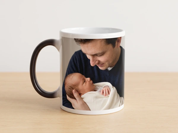 Magic mug with a black handle printed with a father smiling at his newborn