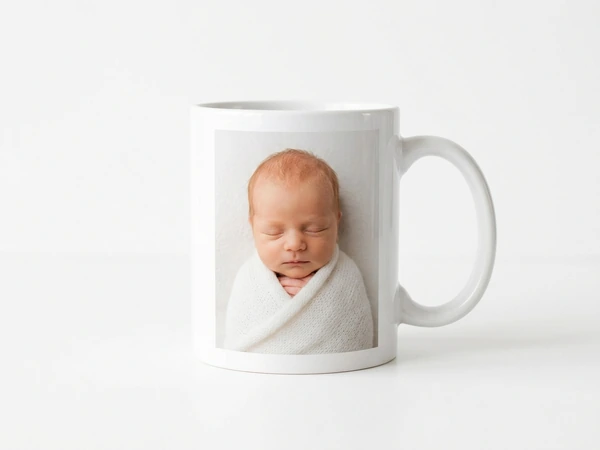 White mug printed with a sleeping newborn in a white wrap