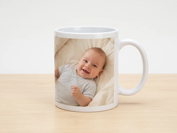 Photo mug printed with a laughing baby lying on a cream blanket